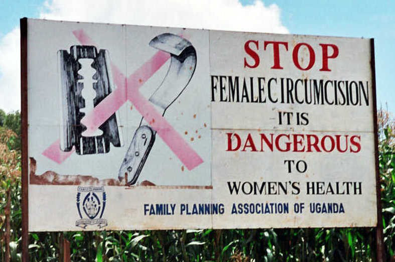 A campaign poster reads “Stop female circumcision. It is dangerous to women’s health. Family planning association of Uganda”. An image on the poster shows a blade with a red X mark slashed across it.