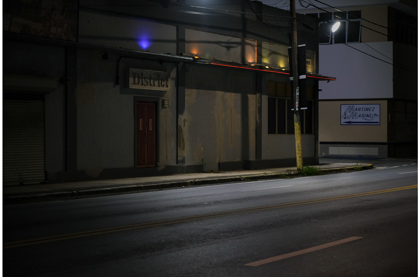 Fig. 1: Image of a building and empty road at night. The door to the building has a sign that reads ""District.