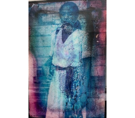 The photographer Chandra McCormick stands in a white dress with her right hand on her camera, at her hip. Her steady gaze directly meets the viewer. The image obscured by blues, purples, and reds, as well as unusual textures, all the result of damage from flooding. 