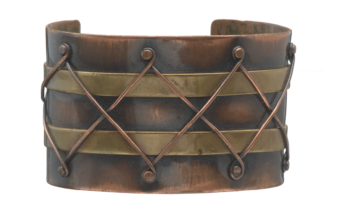  Image of a wide copper bracelet with intricate designs. 