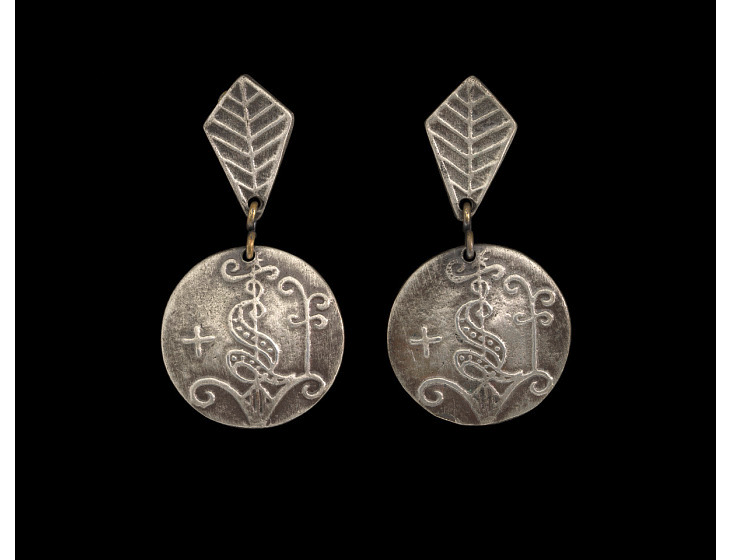 Image of silver earrings resting against a black background. 