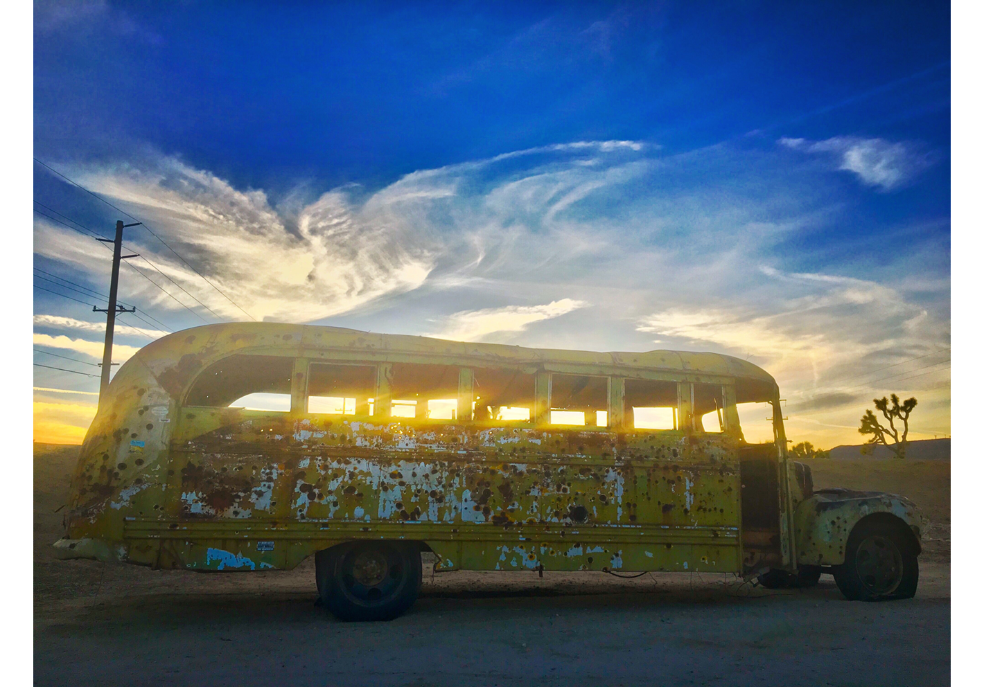 An old, abandoned yellow school bus with a cloud above.