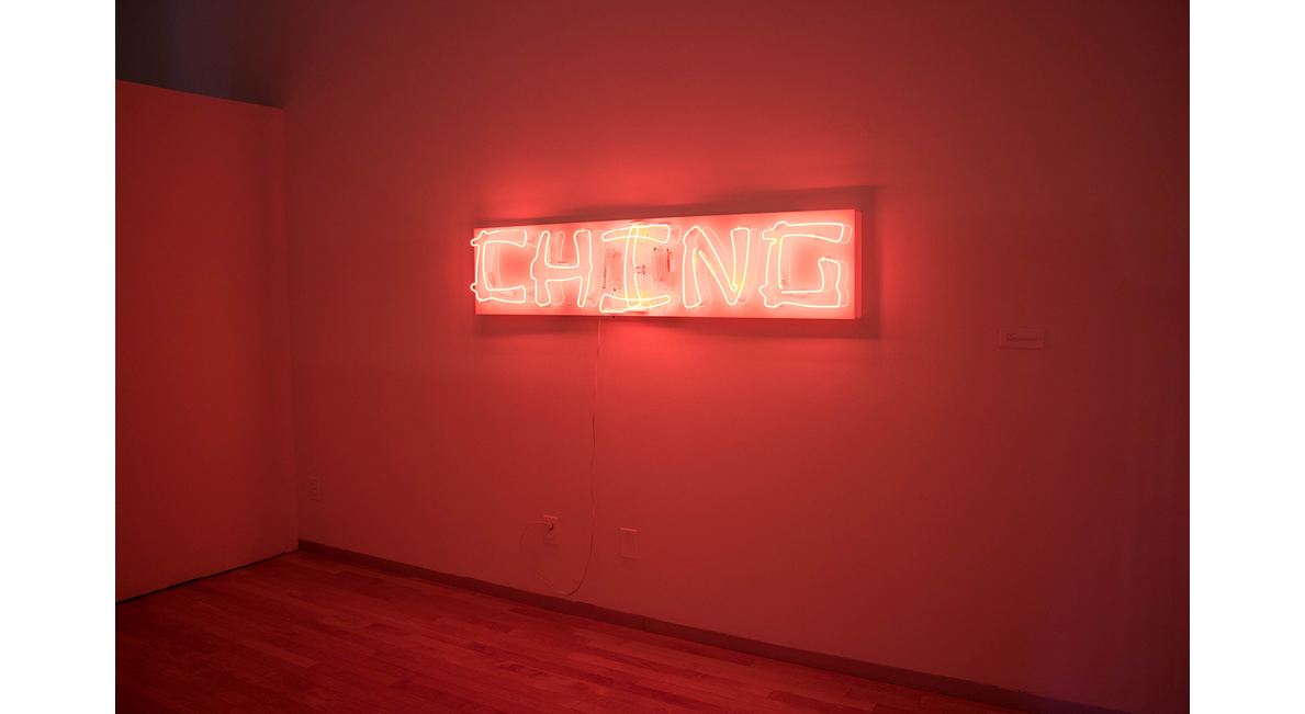 Red glowing neon sign that reads 'Ching' hanging on a wall.