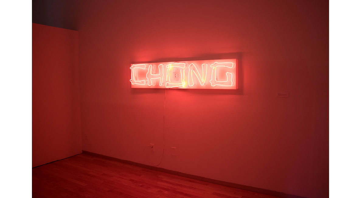 Red glowing neon sign that reads 'Chong' hanging on a wall.