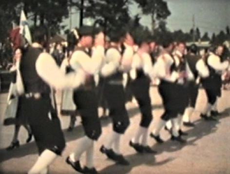 Eighteen folk dancers from Jeppo in traditional costumes dancing their minuet (1977). Men clapping their hands, screenshot by Gunnel Biskop after Kim Hahnsson’s film.