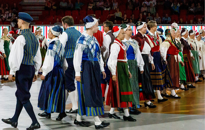 A large group of Finnish Swedish folk dancers in traditional costumes perform a minuet from Oravais in Turku (2017). Partners have passed each other are about to turn around to face each other again, photograph by Timo Hukkanen.