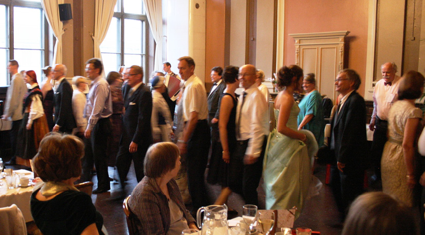 A large group of guests at Gunnel Biskop’s doctoral dinner dance a minuet from Oravais with hop steps (2012). Partners have just passed each other, photograph by Karin Långbacka.