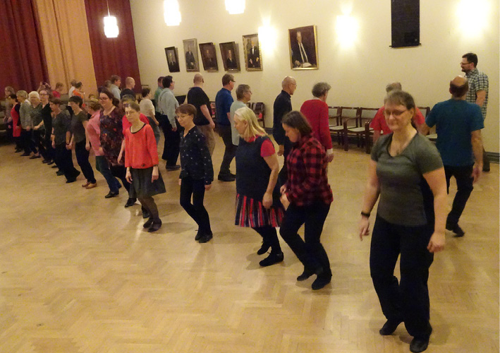 Approximately thirty people are dancing the minuet from Oravais during a dance evening in Helsinki (2019). Photograph by Gunnel Biskop.