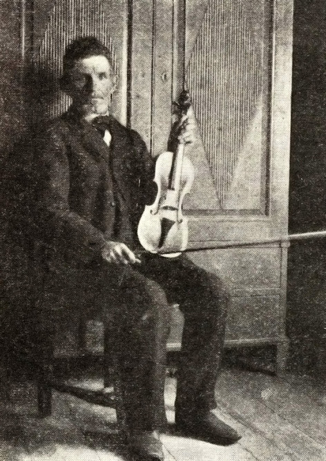 Musician Gustaf Bohm from Kimito sitting with a fiddle. Photograph by Otto Andersson.