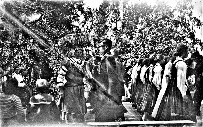 The minuet is danced at a wedding in Vörå. Ostrobothnia (1925), on the left is the bride and groom, the bride with a tall brass crown looks straight into the camera, photograph by Erik Hägglund.