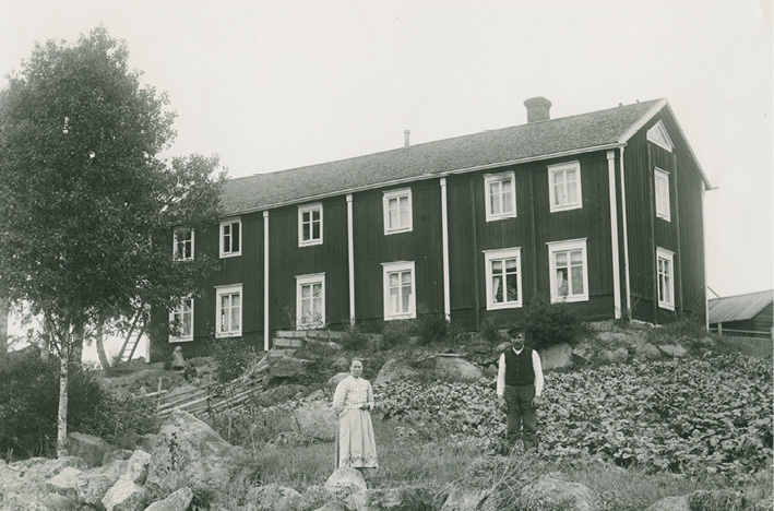 A woman and man in front of a wealthy peasant’s farmhouse in Ostrobothnia (early 20th century). Photograph by Erik Hägglund.