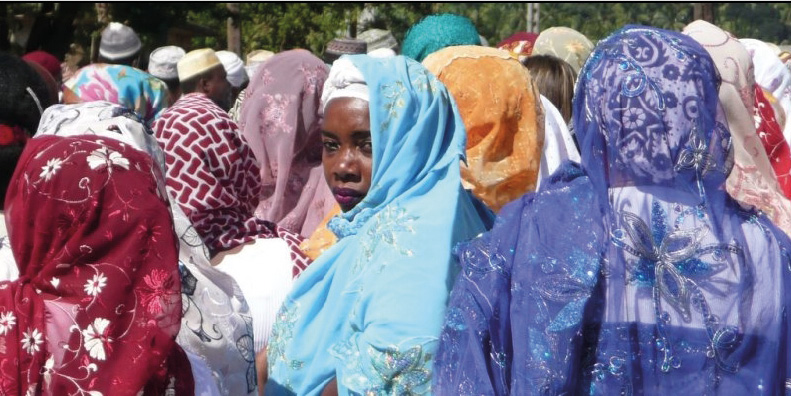 Women and men with colourful hijabs and chechias turn their backs to the camera. Only one woman with a light-blue embroidered hijab has her face turned to the viewer.