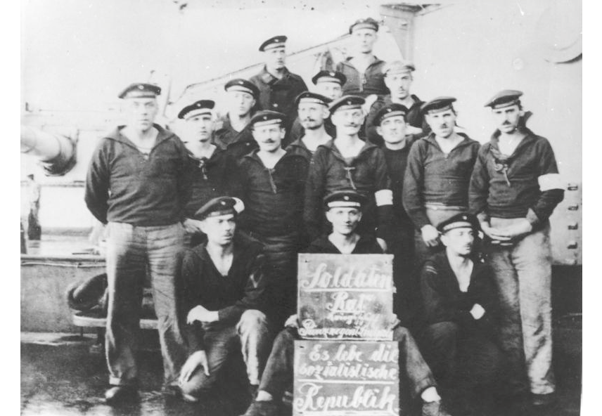 Sailors from the liner “Prinzregent Luitpold” on deck of the ship with plaque reading “Soldatenrat Kriegsschiff Prinzregent Luitpold