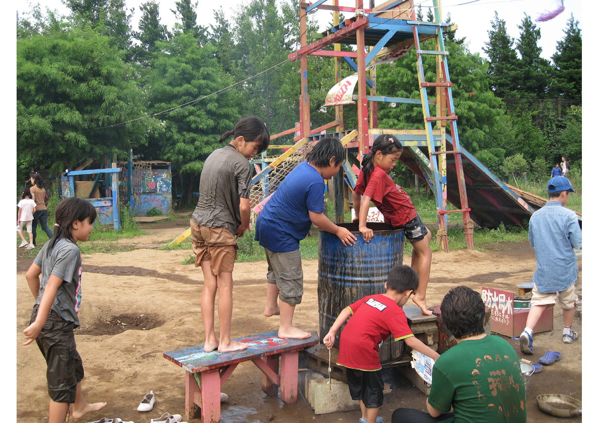 School-aged children climbing on bench and oil drum in adventure playground