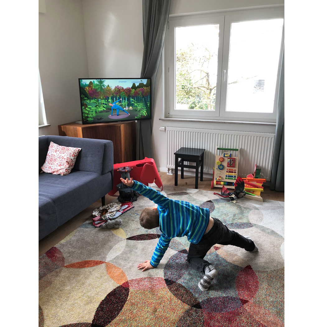 Interiror. Small child doing yoga, mirroring image on TV Screen.