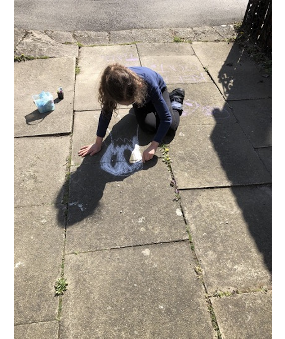 Photo of child drawing ghost-like face on street pavement