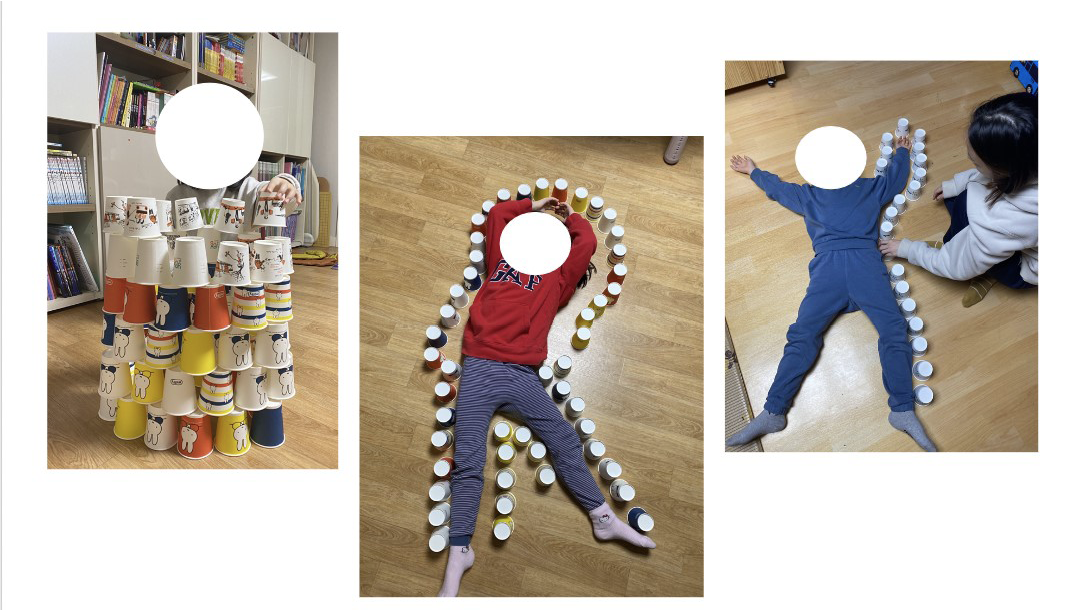 The three photos show how young children play with paper cups at home. The first photo shows a child piling up a round tower with various coloured paper cups. The second photo shows a girl lying with open arms and paper cups around her. She wore a red sweatshirt and purple stripe pants. The third photo displays a boy and a mother. She puts paper cups around him. The boy wore a blue sweatshirt and trousers.