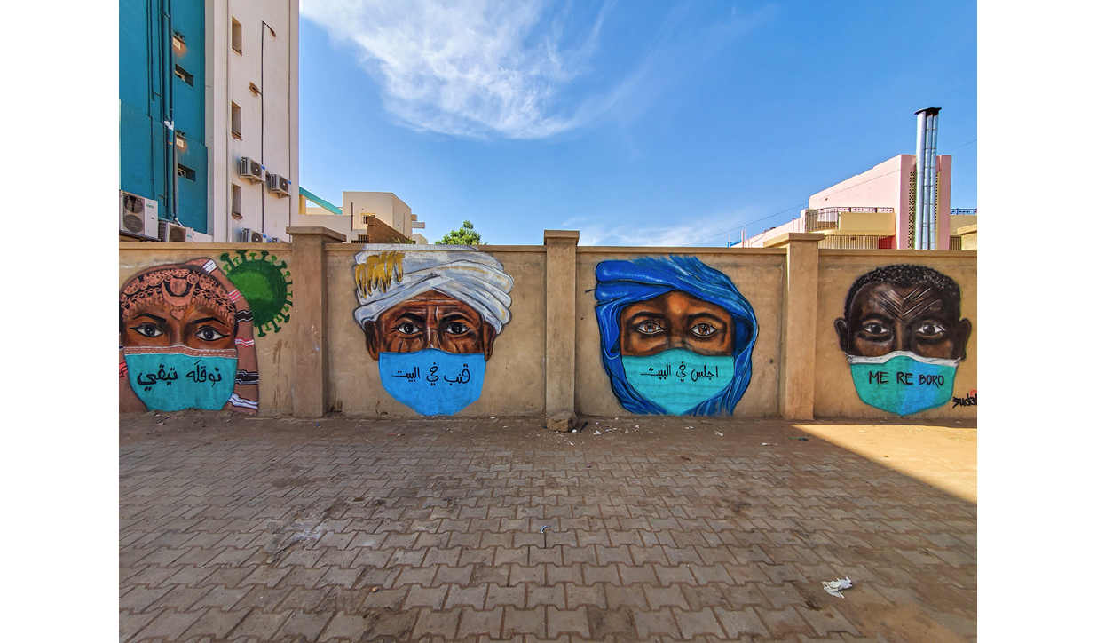 Four large, highly detailed, spray painted portraits of individuals wearing head coverings, each in a different style. Each figure is wearing a surgical face mask with text reading 'stay at home' written in a different language