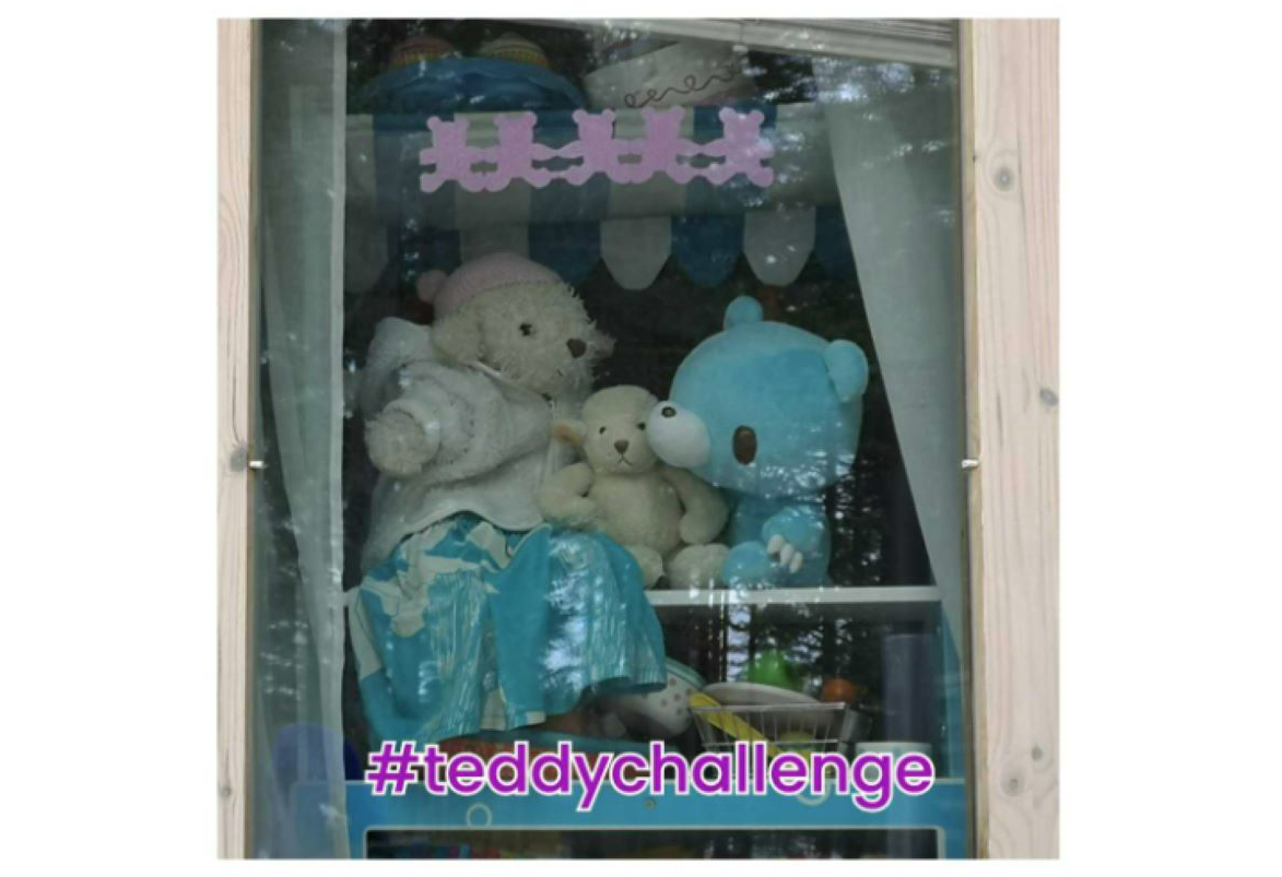 Three teddy bears arranged on a shelf and facing out of the window