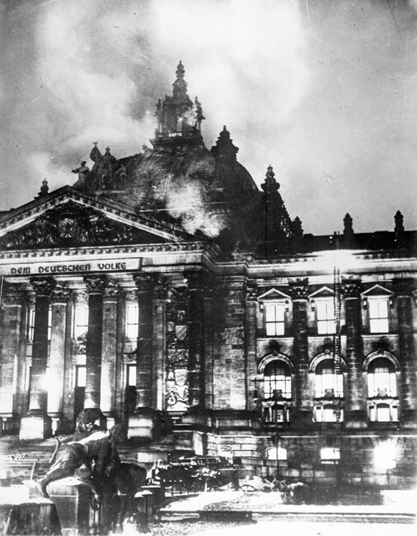 A black and white photograph of German fireman attempting to quell the flames at the Reichstag building in Berlin being burnt