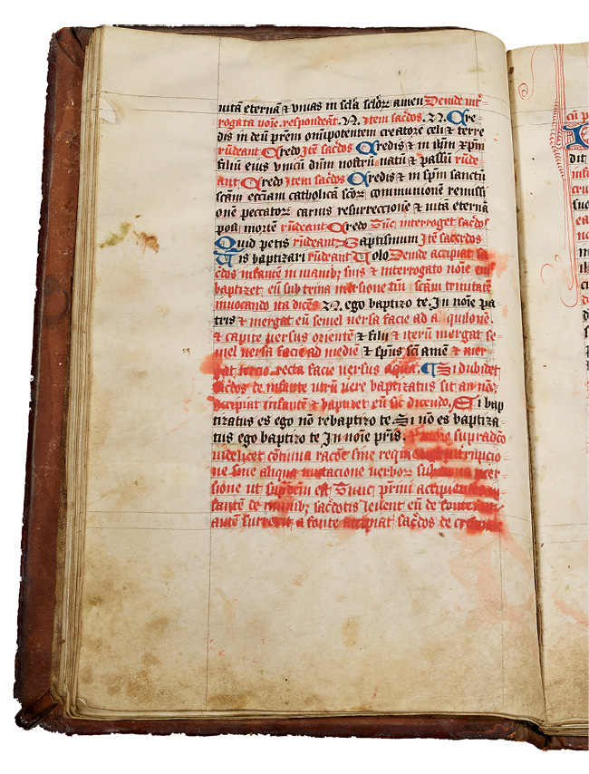 Left half of an opening, with a rubricated noted ritual made in England in the fifteenth century. It contains instructions for performing a Baptism. Holy water that has splashed on the book has caused the red ink to run.