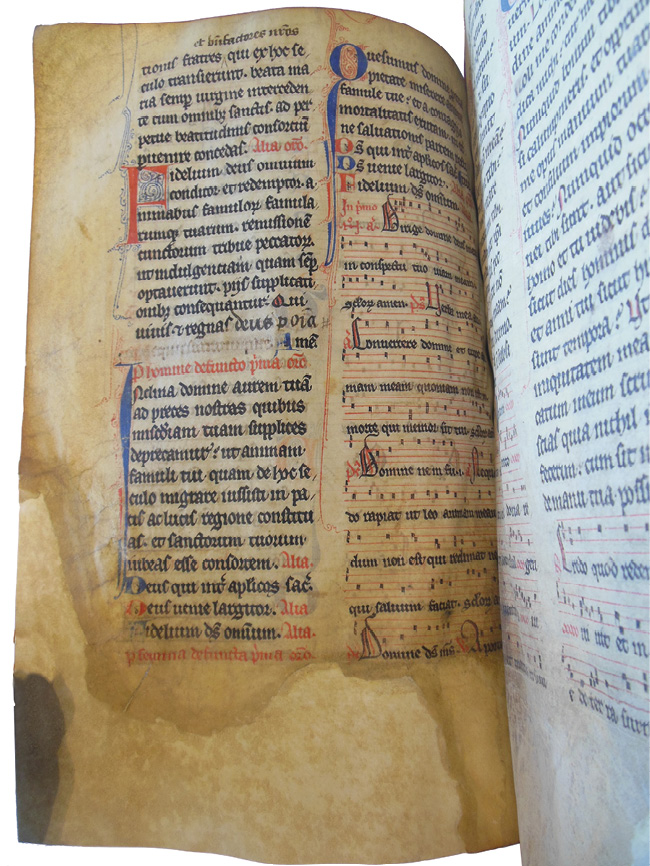 Left half of an opening of the Grand Obituary of Notre-Dame showing a noted Mass for the dead, where the bottom third of the page is browned and degraded, and the corners have been repaired. The repair is made more visible with backlighting.