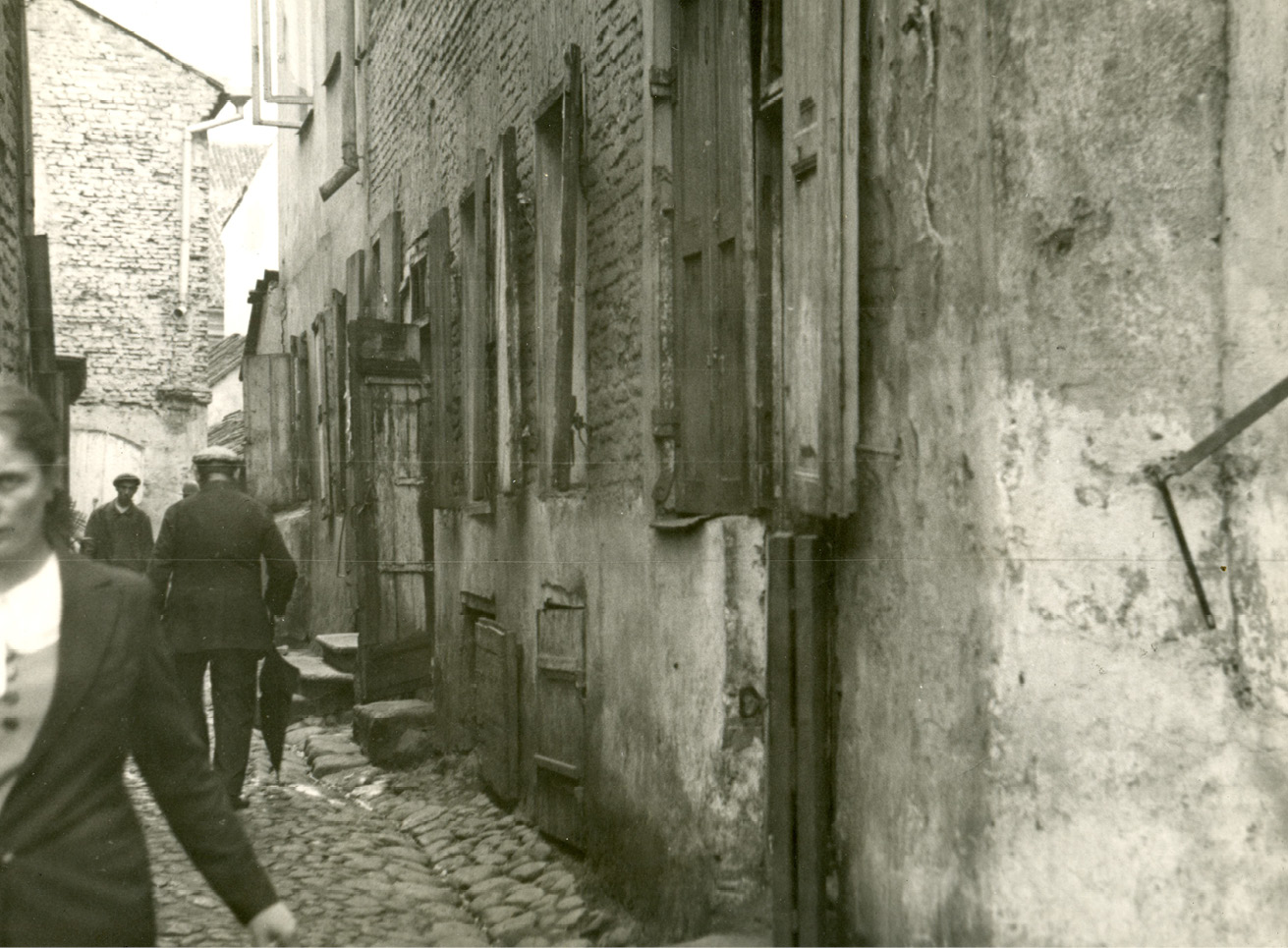Close up of people walking on a narrow cobblestone street between buildings in Baluty, Poland.