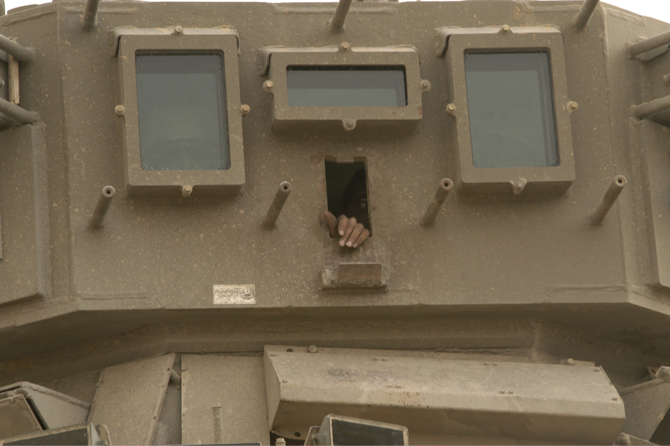 Close-up of an Israeli soldier’s hand placed on the edge of a rectangular vertical opening in the side of an armoured observation post.