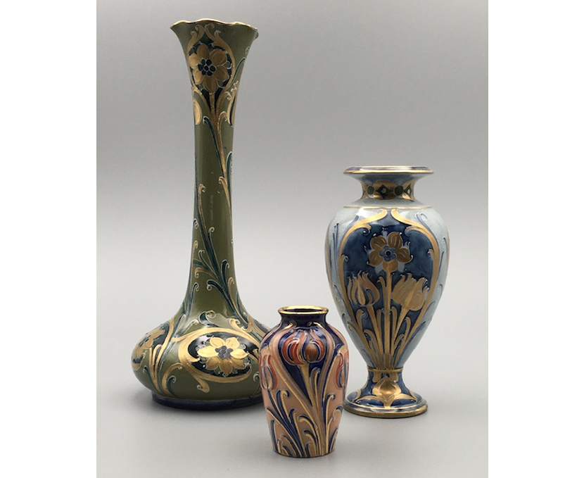 A slender vase with gilded narcissi on a green ground; a squat vase with tulips in red and blue enamels and gilded detail on a salmon pink ground; a pale blue urn with gilded tulips and narcissi in a dark blue panel.,,,