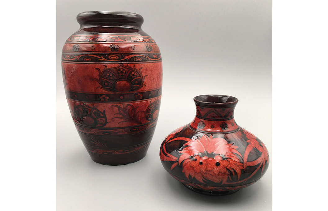 Two decorated vases under a deep-red flambé glaze: one with bands of stylised peacock feathers, forget-me-nots and swirls; the other with a cornflower motif between bands of chevrons and forget-me-nots.",,,