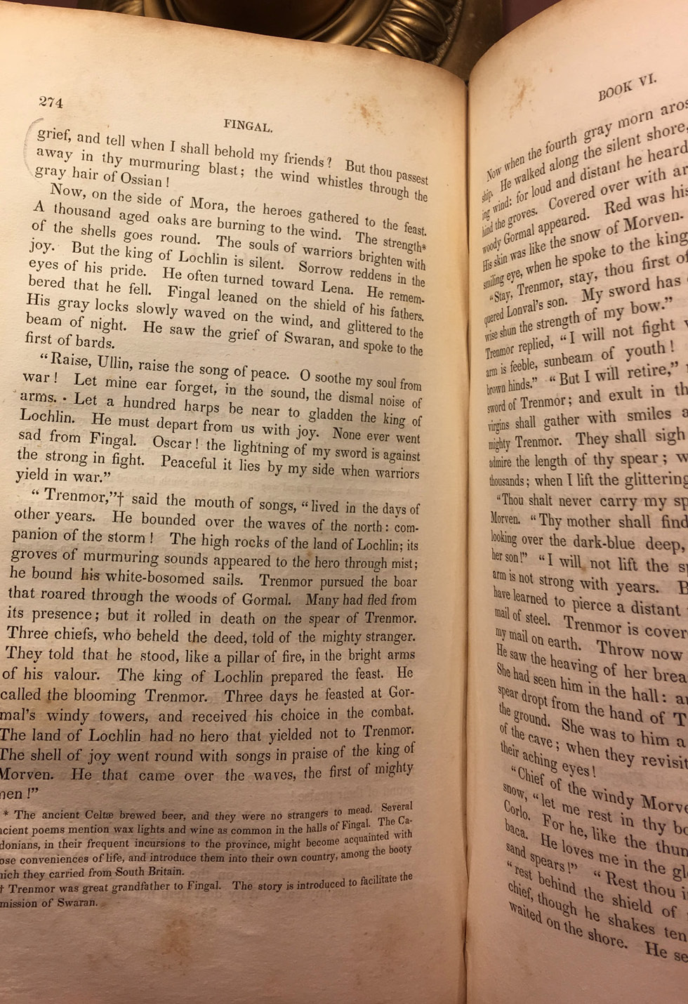 An old printed book with mottled pages held open on page 274, with the base of a brass table lamp visible behind the book.