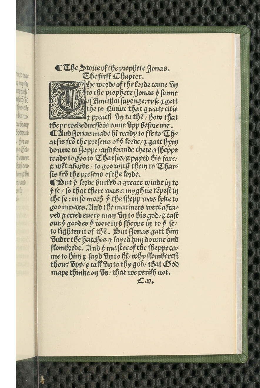 A printed book with a green cover opened on an unnumbered page. It is the right-hand page and contains prose text and a decorated initial letter.