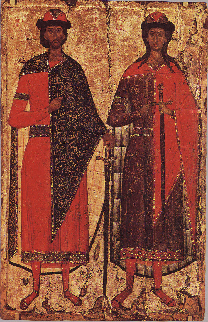 An image of two men dressed in fine, colourfully embroidered clothing, both wear caps and cloaks over one shoulder and hold a sword.