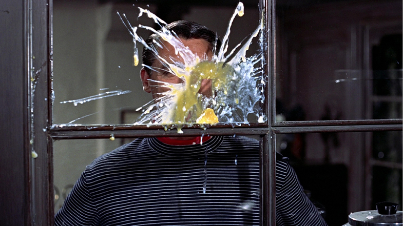 A comedic moment from Alfred Hitchcock’s ‘To Catch a Thief’ (1955), where a man gets hit in the face with a splatter of eggs while looking through a glass window. This slapstick-like visual gag contrasts with the film’s usual tone of suspense and romantic tension.”,