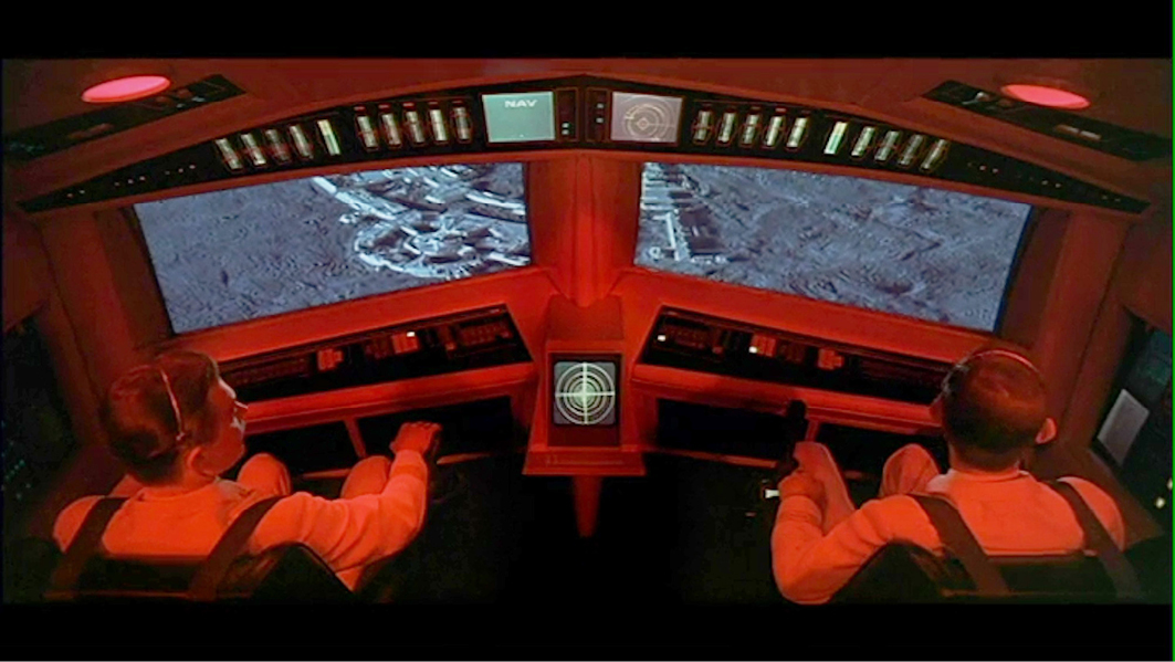A cockpit view from “”2001: A Space Odyssey”” with astronauts looking at a detailed lunar surface on the screens in front of them as they navigate their shuttle.”,