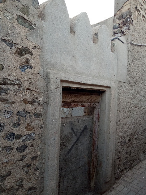 Photo of a traditional Omani doorway embedded in a wall of mud bricks and mortar