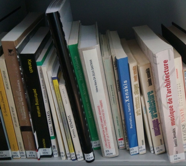 Bookshelf filled with various music and architecture books; prominent titles include works on Xenakis, Kanach, and associated disciplines. The books are organized with spine labels, and they focus on both theoretical and practical aspects.