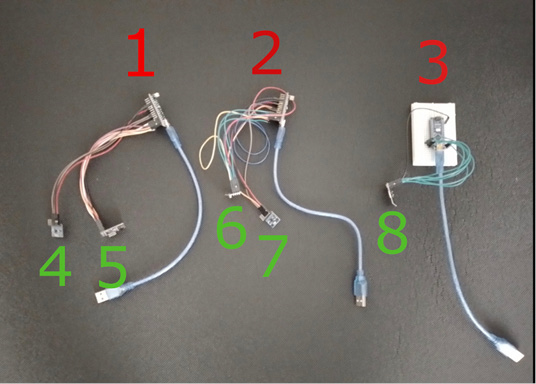 A black surface with eight electronic components. Each component has a mix of wires and connectors, labeled in red (1, 2, 3) and green (4, 5, 6, 7, 8). Components 1, 2, 4, 5, and 6 have USB cables attached. Component 3 is mounted on a white board.