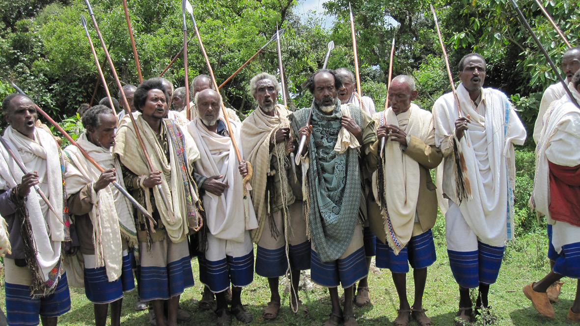 Photograph of Guji adults standing in a raw and singing qexala song in a chorus