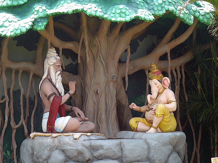 The Hindu sage Vyasa dictating the Mahabharata to Lord Ganesha, set under a sacred tree with elaborate roots and foliage.